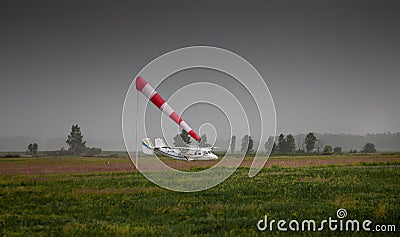 Windsock, weather vane for airfields. Red and white striped fabric showing wind speed, strength and direction. Umbrella cap at the Editorial Stock Photo