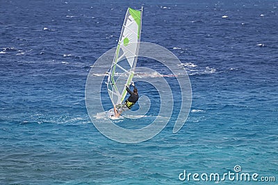 Windsurfer on a board under a sail against the background of the sea, wind and waves. Editorial Stock Photo