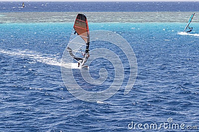 Windsurfer on a board under a sail against the background of the sea, wind and waves. Stock Photo