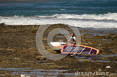 Windsurfer carrying his windsurf board. Editorial Stock Photo