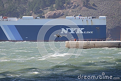 Windsurfer lifted into the air against the backdrop of a NYK Line ship above white caps beneath the Golden Gate Bridge. Editorial Editorial Stock Photo