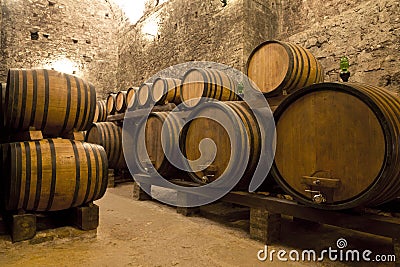 Wine barrels stacked in the old cellar of the winery. Stock Photo