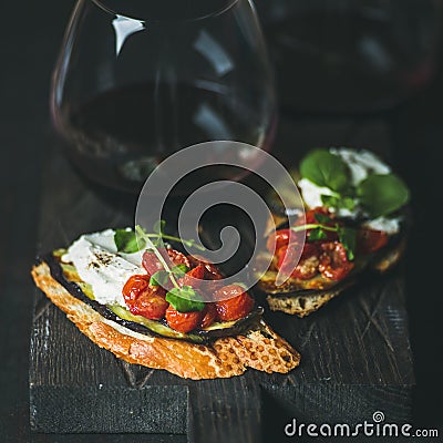 Wine, brushetta with eggplant, tomatoes, garlic, cream-cheese and arugula Stock Photo