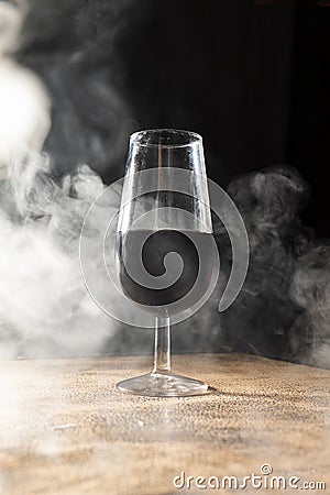 wine glass enveloped by white smoke with black background Stock Photo