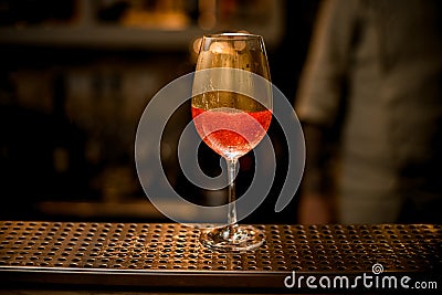 Wine glass with fizzy drink decorated with gold stands on bar counter Stock Photo