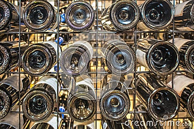 Wine in a metal wrack - view of bottoms of bottles of a variety of brands - selective focus background Editorial Stock Photo