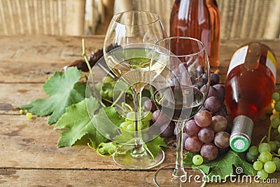 Wine tasting concept. Two glasses of red an white wine, grapes and two bottles of pink Stock Photo