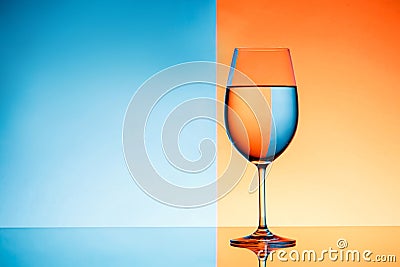 Wineglass with water over blue and orange background. Stock Photo