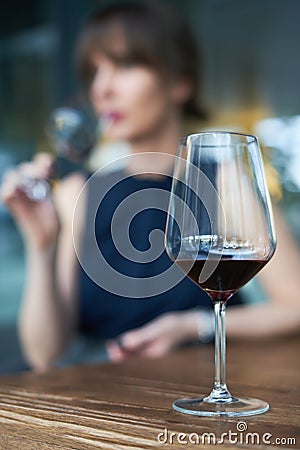 Winetasting concept. Focus on wineglass, woman drinking wine in the background Stock Photo