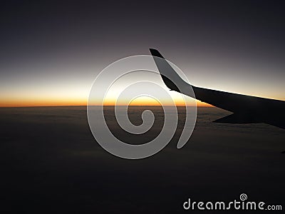 Wing of aircraft flying at dawn Stock Photo