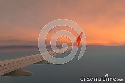 Wing airplane against the sunset sky above the cloud. Stock Photo