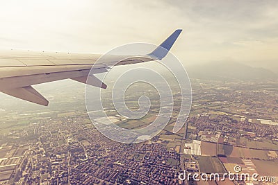 Wing of an airplane flying above towns and villages Stock Photo