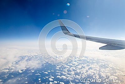 Wing of an airplane in the sky above the blue clouds Stock Photo