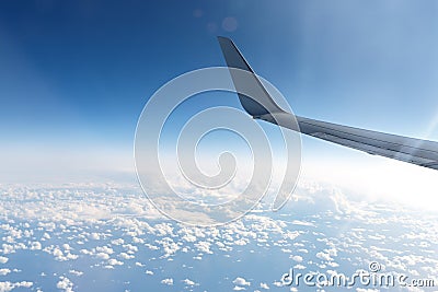 Wing of an airplane in the sky above the blue clouds Stock Photo