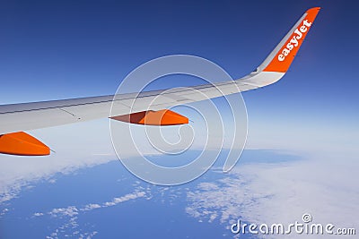 The wing and winglets of an Airbus A320 commercial airliner with a company logo while in flight Editorial Stock Photo