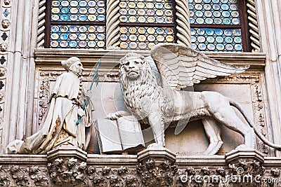 Winged Lion and a priest. Detail of the Doge`s Palace Palazzo Ducale in Venice, Italy. Stock Photo