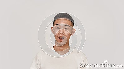 Wink. Portrait of young asian man with clean shaven face looking cheerful, winking at camera isolated over white Stock Photo