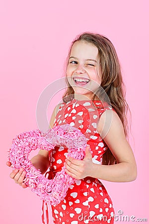 Winking girl holding rosy heart on pink background Stock Photo