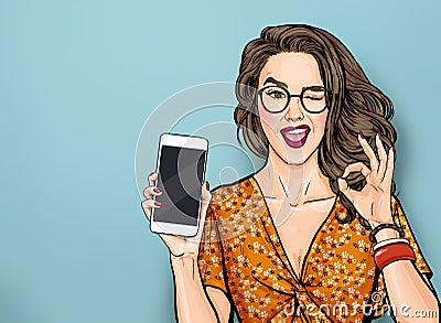 Winking woman in glasses showing smart pone and OK sign. Pop art girl holding phone. Digital advertisement female model Stock Photo