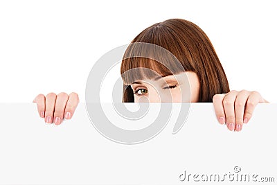 Winking woman peeking over blank billboard Stock Photo