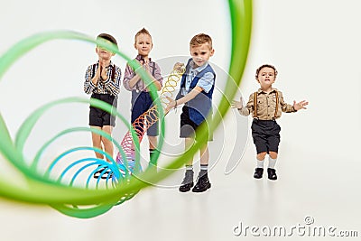 Winner. Boys, children in classical retro clothes playing with slinky toy over grey studio background. Concept of game Editorial Stock Photo