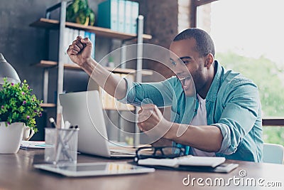 Winner! A dream of the young afro american entrepreneur came true. He is very excited, wearing smart casual, celebrating in the of Stock Photo