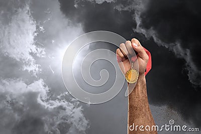 Winner raising hand with gold medal up to stormy sky, closeup. Space for text Stock Photo