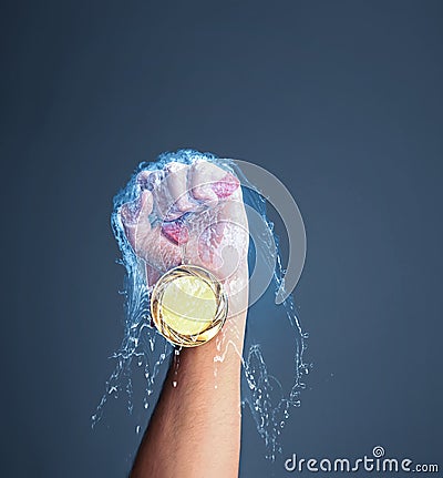 Winner raising hand with gold medal through water splash on dark grey background, closeup Stock Photo