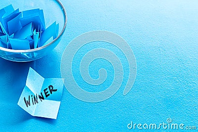 Winner selection. Paper pieces for lottery in vase on blue background copy space Stock Photo