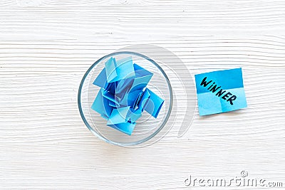 Winner selection. Paper pieces for lottery in vase on white wooden table from above Stock Photo