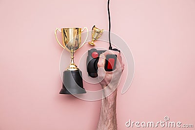 Winning gamer. Hand using a retro games joystick with a gold winning trophy Stock Photo