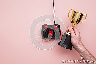Winning gamer. Hand using a retro games joystick with a gold winning trophy Stock Photo