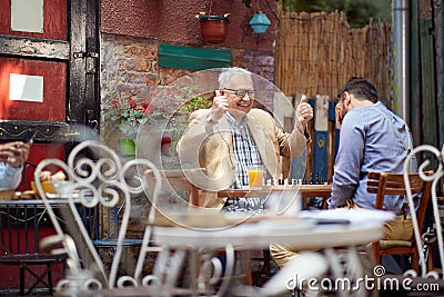 Winning and loosing in chess. older caucasian male smiling with thumbs up. young guy with his hand over his eyes Stock Photo