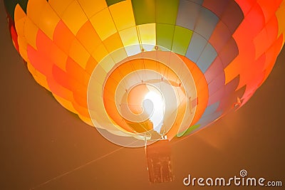 Colorful hot air balloon flying with flames against dark sky at night Stock Photo