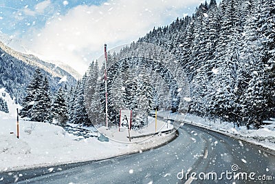 Winter alpine road curve landscape with forest, mountains and blue sky on background at bright cold twilight time. Car Stock Photo