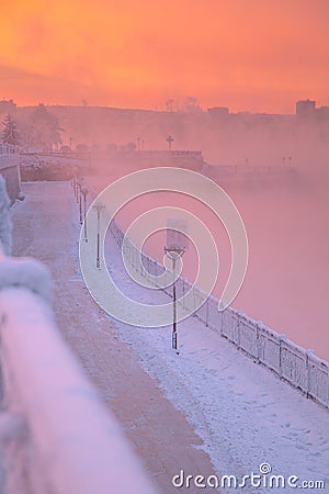 Winter beautiful sunset and mist above the water of river. Frosty weather, trees are covered with fluffy hoarfrost - urban winter Stock Photo