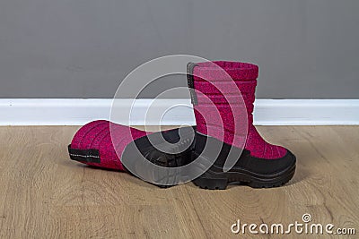 Winter boots snowboots dark pink with black soles on the floor in the room Stock Photo