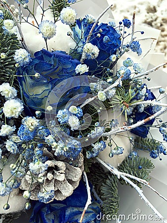 Winter bouquet of white and blue flowers. Flowers bouquet including Blue roses covered with snow, cones, fir branches, cotton ball Stock Photo