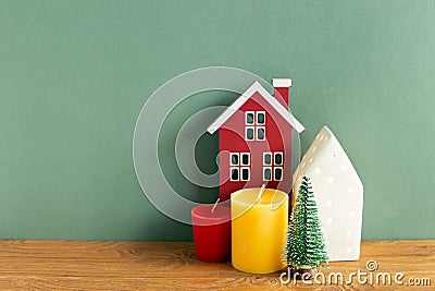 Winter christmas concept. Candle, house model, tree on wooden table. green background Stock Photo