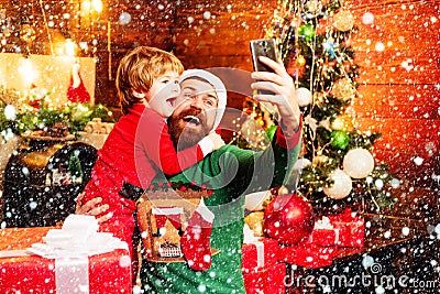 Winter Christmas emotion. Little Santa and old bearded Santa using smartphone. Internet, wireless and social media Stock Photo