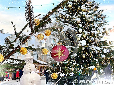 Winter city Christmas tree illuminated ,snowman and pine branch with gold confetti and red ball ,people walk ,snowy Tallinn old to Stock Photo