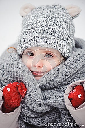 Winter close up vertical portrait of adorable smiling baby girl in grey knitted hat and scarf Stock Photo