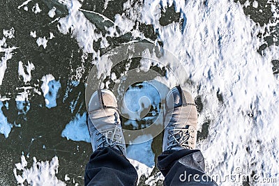 In winter Concept Man wear hiking boots standing on a frozen ice rive covered snow Stock Photo