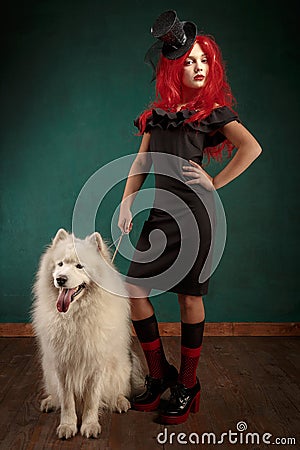 Winter dog holiday and Christmas. Girl in a black dress and with red hair with a pet in the studio. Christmas woman with Stock Photo