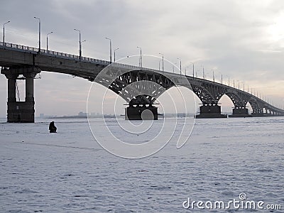Winter fishing on the ice. The Volga river in Saratov, Russia. Road bridge on the horizon Stock Photo
