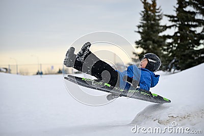 Winter Fun - Child Sledding/Tobogganing Fast Over Snow Ramp Stock Photo