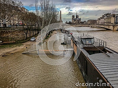 Long gangplank stretches from houseboat nearly to the shore of the flooded Seine River in Paris, France Editorial Stock Photo