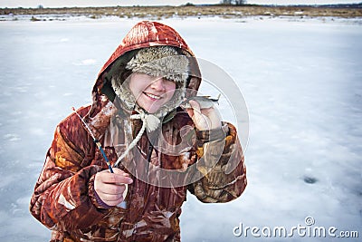 In winter, a girl in overalls caught a roach fish on the river Stock Photo