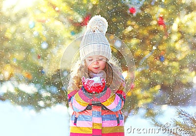 Winter happy little child holds blowing snow on hands Stock Photo