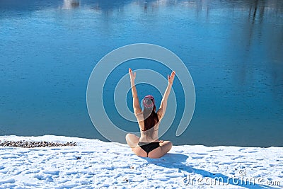 Winter hardy woman back view body with raised hands up on snow - white bank of the blue lake background copy space Stock Photo